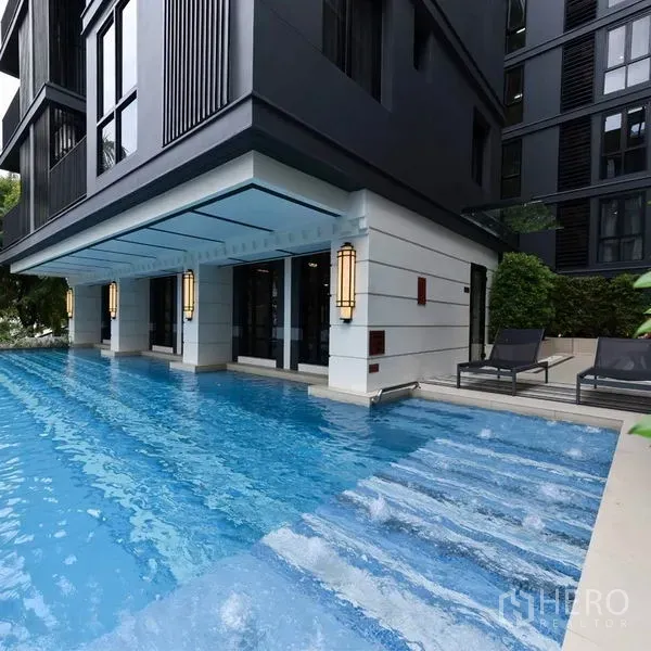Condominium for rent in Pathum Wan, Bangkok - Condominium swimming pool with sun loungers beside a modern low-rise facade.