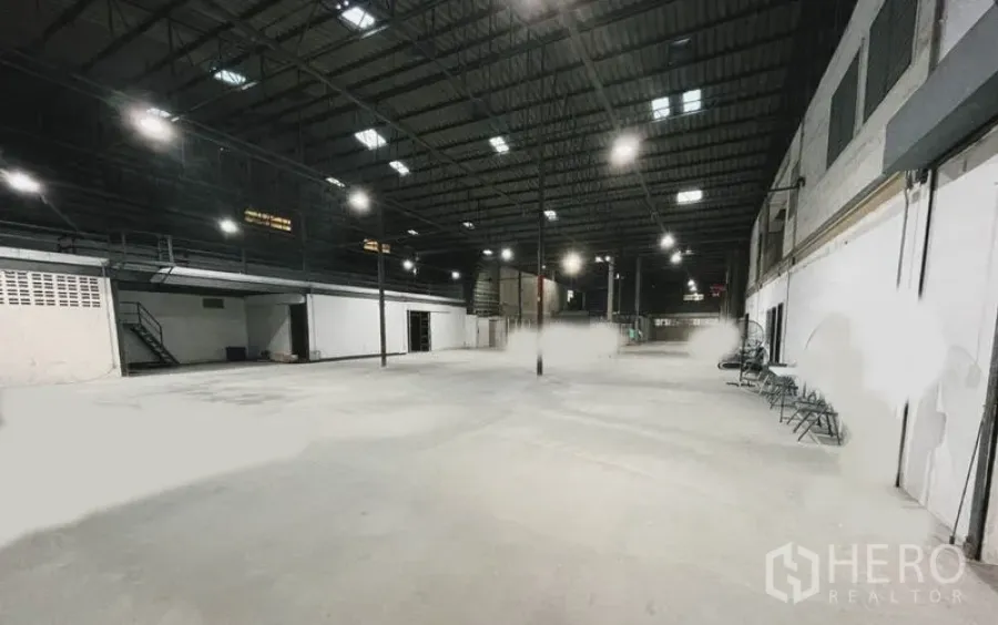 Warehouse for rent or sale in Mueang Nonthaburi, Nonthaburi - Panoramic view of a clear-span warehouse hall with skylights, bright lighting, and central support columns.