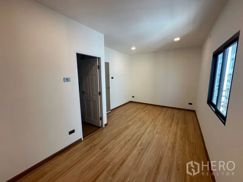 Home Office for rent in Wang Thonglang, Bangkok - Bedroom with warm wood flooring, recessed lights, and a side window.