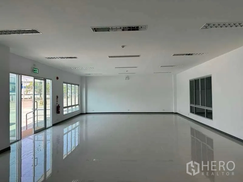 Factory for rent in Bang Sao Thong, Samut Prakan - Bright ground-floor office with full-height windows and sliding glass doors overlooking the forecourt.
