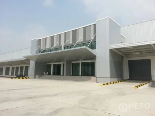 Warehouse for rent in Bang Sao Thong, Samut Prakan - Modern warehouse office frontage with glass facade, roller shutter loading dock, and wide truck-friendly apron.