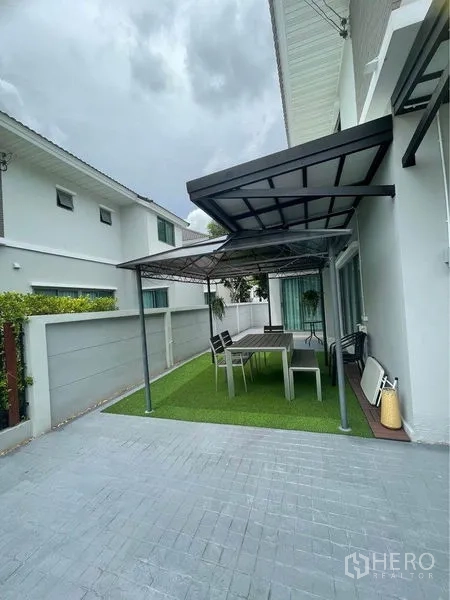 独立式住宅 出售在Lat Krabang, Bangkok - 侧院带顶棚的露台，户外餐桌椅与人造草坪。
