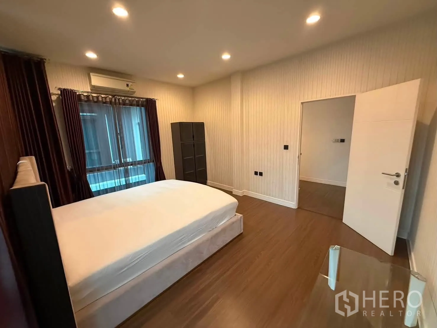 Detached House for rent in Bang Kapi, Bangkok - Bedroom with upholstered bed, curtains, wood flooring, and air conditioner.