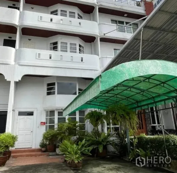 带办公室的家 出租在Bang Rak, Bangkok - 多层白色外立面的居家办公楼，前方有绿色雨棚车位。