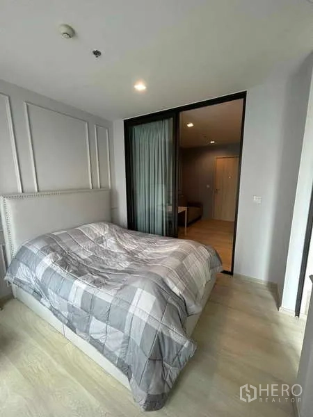 公寓 出售在Pathum Wan, Bangkok - 从卧室望向客厅的视角，玻璃滑门与浅色木地板相映。