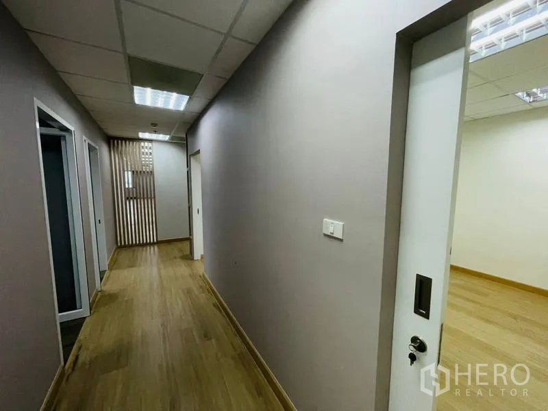 Office Space for rent - Corridor with wooden floor leading to glass-partitioned meeting rooms.