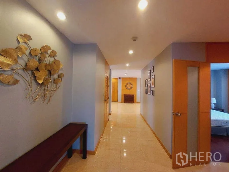 Apartment for rent - Long hallway with recessed ceiling lights, decorative wall art and glossy tiled flooring.