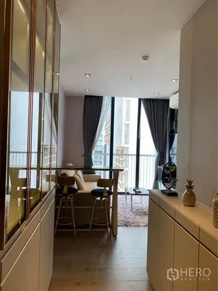 Condominium for sale - Open-plan living area with bar counter, sofa, floor-to-ceiling windows and balcony in Phrom Phong condo.