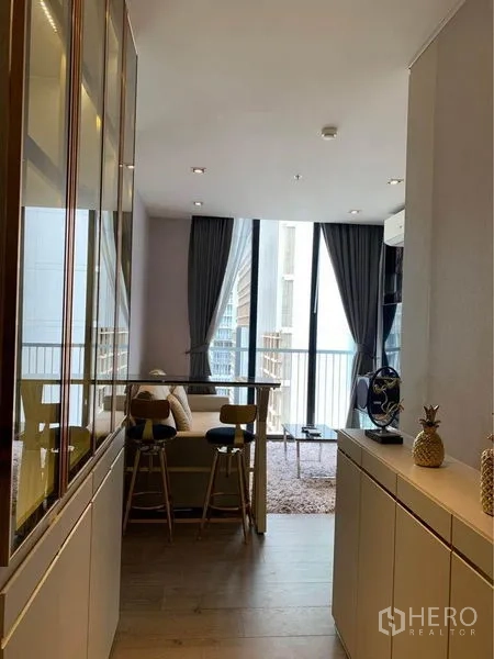Condominium for sale - Open-plan living area with bar counter, sofa, floor-to-ceiling windows and balcony in Phrom Phong condo.