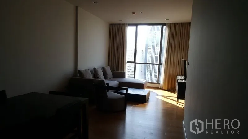 คอนโด ให้เช่าในWatthana, Bangkok - ห้องนั่งเล่นกว้าง โซฟาเข้ามุม พื้นไม้ และหน้าต่างกระจกเต็มผนังมองเห็นวิวสกายไลน์กรุงเทพฯ