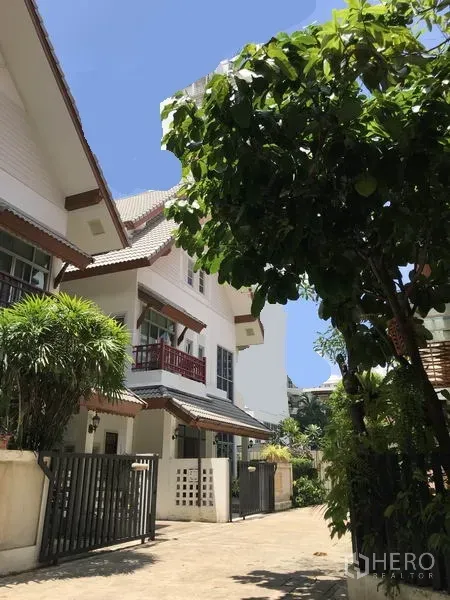 独立式住宅 出租在Khlong Toei, Bangkok - 独栋别墅外观，带大门与阳台，社区绿树成荫。