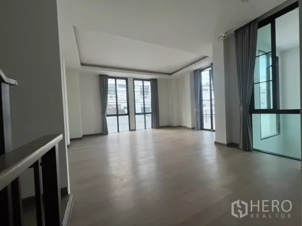 Detached House for rent in Lat Phrao, Bangkok - Spacious upstairs family area with wood floors, multiple sliding doors to balconies and abundant natural light.