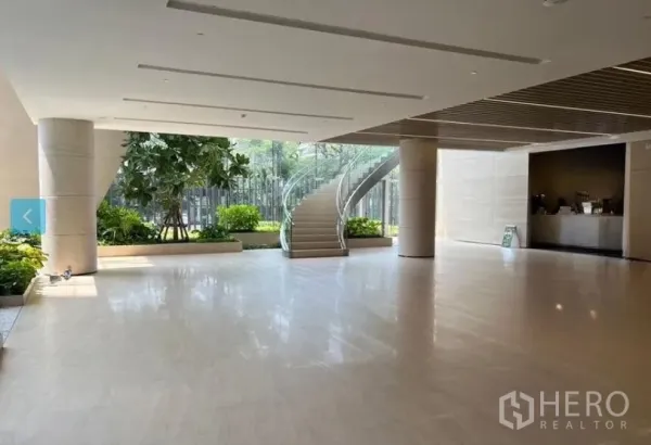 Retail Space for rent - Spacious modern lobby with polished stone floors, indoor planters, floor-to-ceiling glass and a curved glass staircase.
