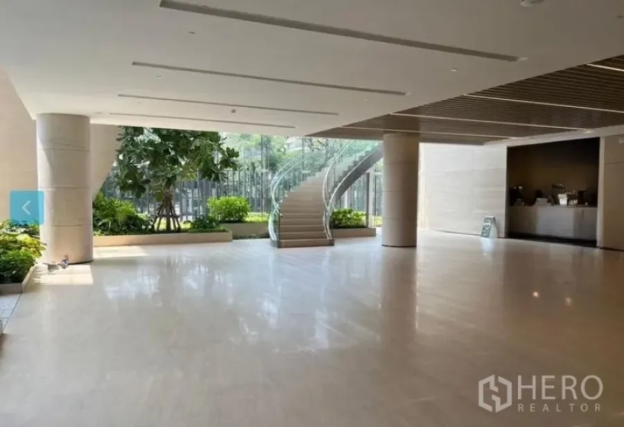 Retail Space for rent - Spacious modern lobby with polished stone floors, indoor planters, floor-to-ceiling glass and a curved glass staircase.