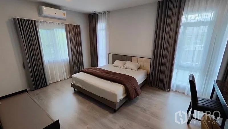 Detached House for rent in Prawet, Bangkok - Airy secondary bedroom with large windows, wood floors and air conditioning.
