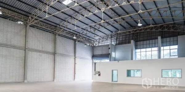 Warehouse for rent in Mueang Samut Sakhon, Samut Sakhon - Spacious warehouse interior with high steel truss roof, skylights, polished concrete floor, and built-in office block.