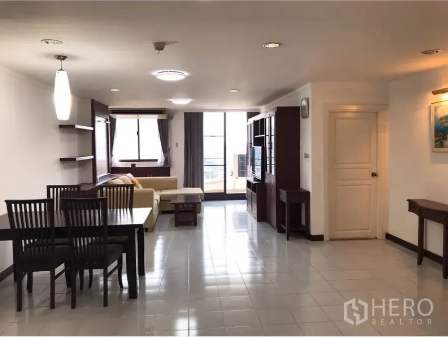 Condominium for rent or sale in Watthana, Bangkok - Spacious open-plan living and dining room with tiled floors and balcony at the far end.