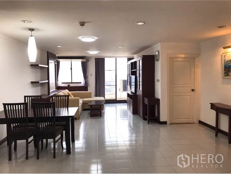 Condominium for rent or sale in Watthana, Bangkok - Spacious open-plan living and dining room with tiled floors and balcony at the far end.