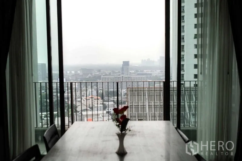 公寓 出租或出售在Bangkok - 餐桌面向阳台，远眺城市天际线。