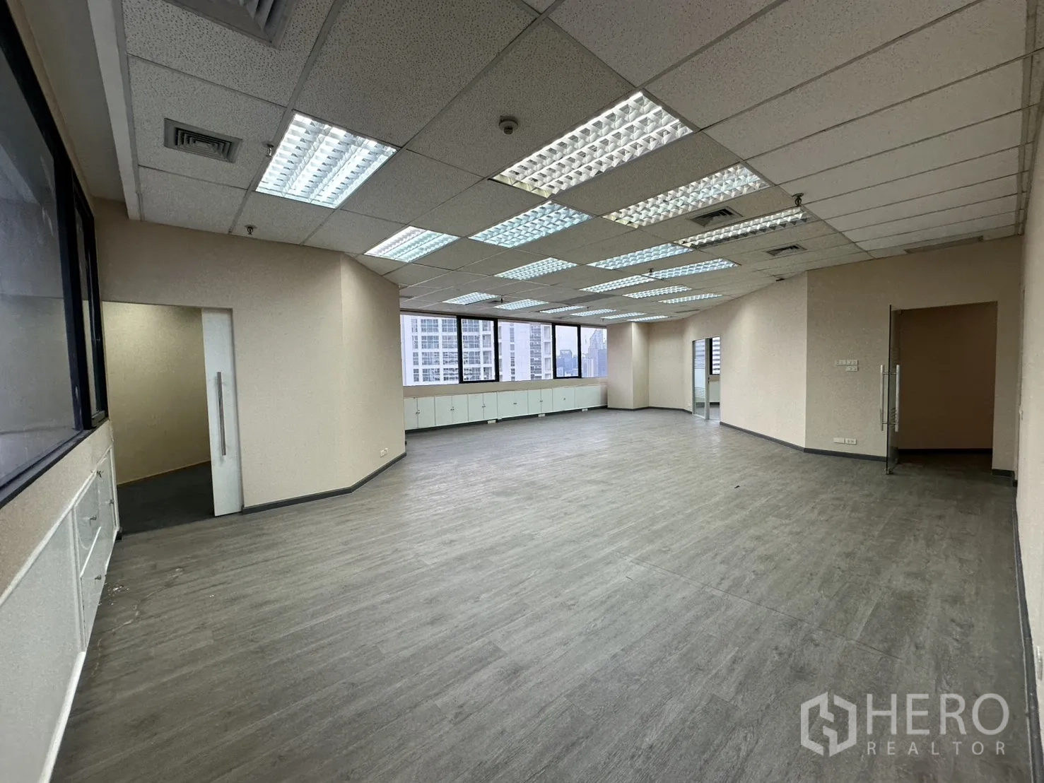 Office Space for rent in Bang Rak, Bangkok - Large open-plan office with fluorescent grid lights and city-view windows.