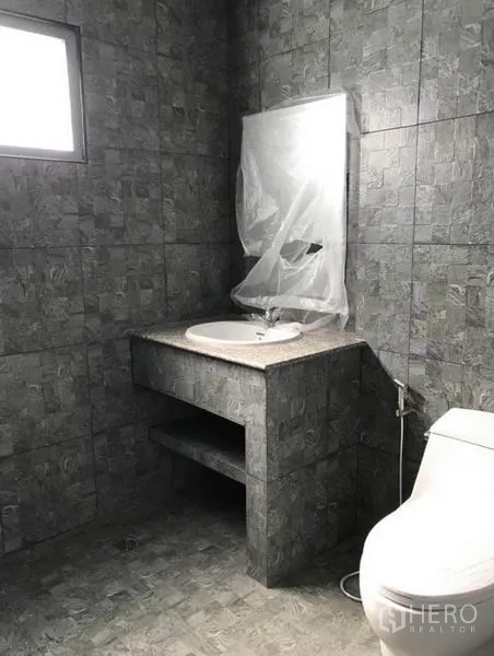 Townhouse for rent in Suan Luang, Bangkok - Second bathroom with gray tiled walls and a built-in vanity with basin.