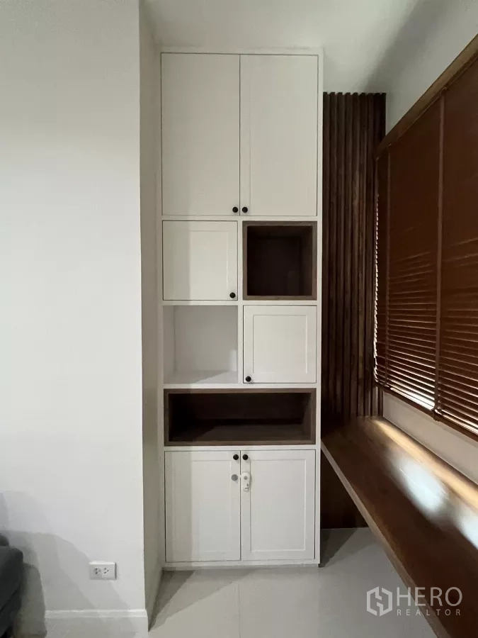 公寓 出租在Bang Kapi, Bangkok - 客厅高柜，白色储物柜靠窗与百叶帘。