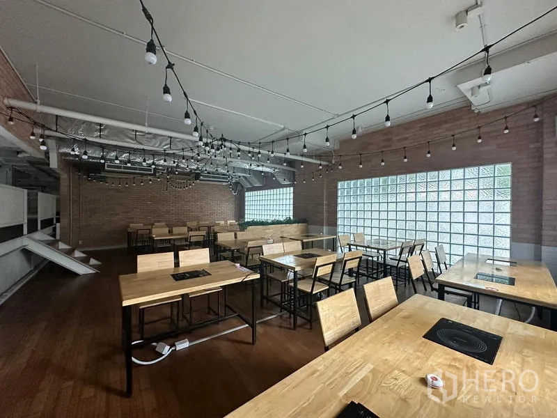 Retail Space for rent in Watthana, Bangkok - Upper dining zone with wooden tables, built-in hobs and string lights.