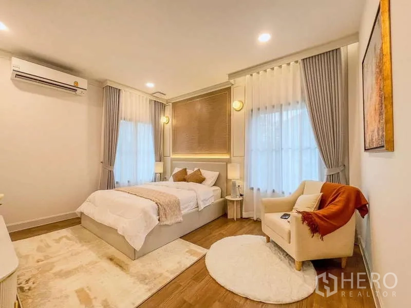 Detached House for rent in Saphan Sung, Bangkok - Warm bedroom with accent wall, armchair and ambient lighting.