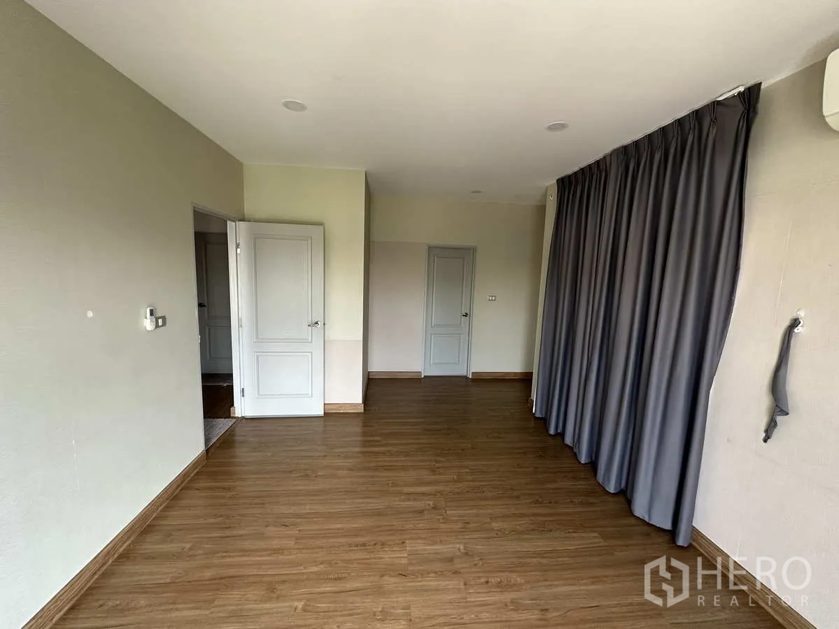 Detached House for rent in Khlong Luang, Pathum Thani - Spacious master bedroom with wood flooring and full-height curtains.