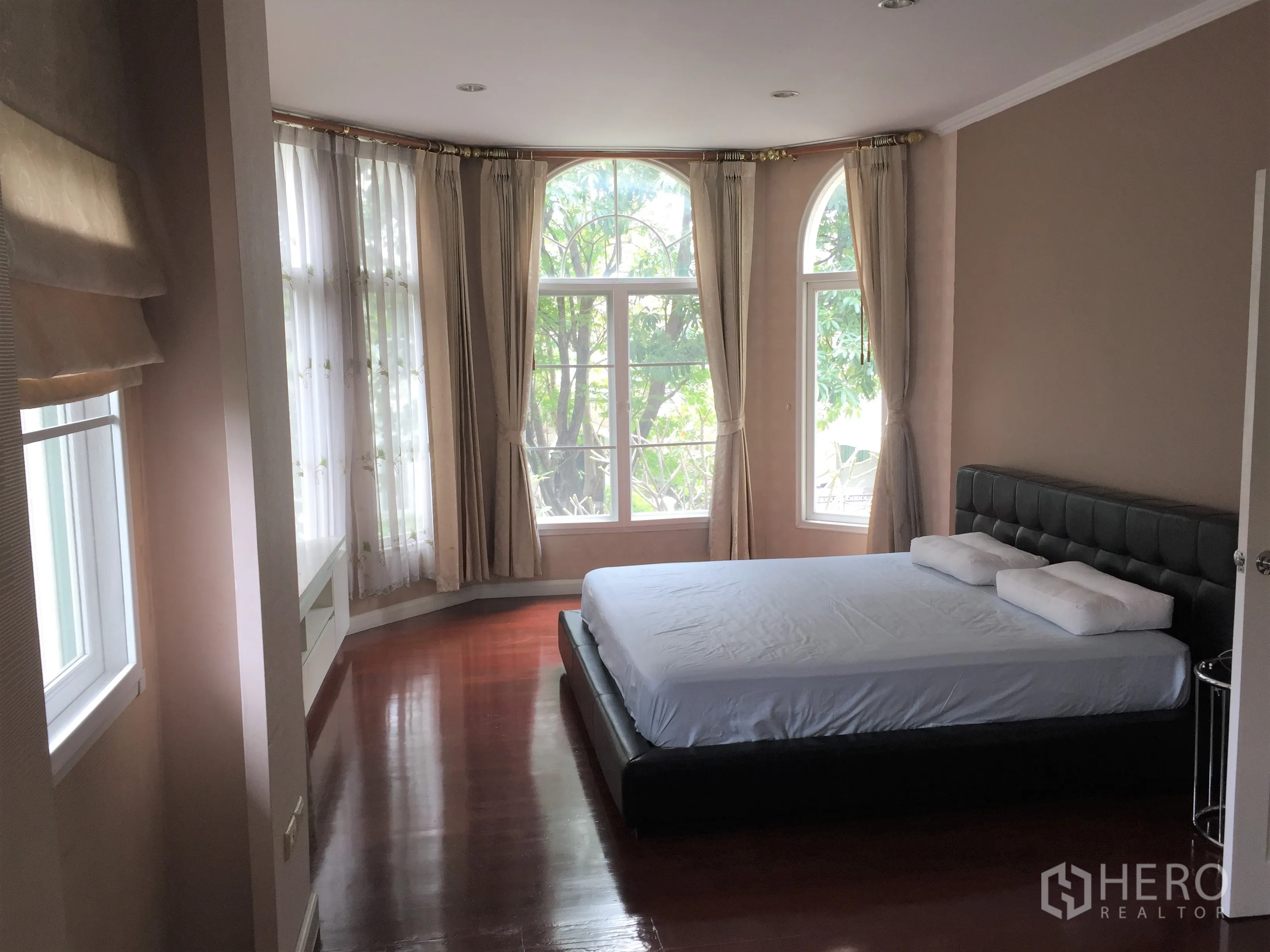 Detached House for rent or sale in Lat Phrao, Bangkok - Second bedroom with floor-to-ceiling corner windows and polished wooden flooring.