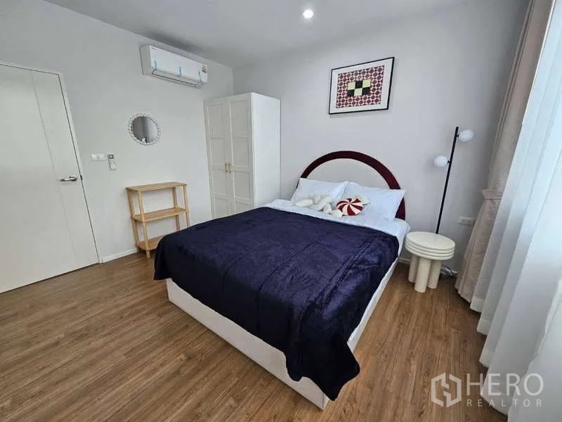 Townhouse for rent in Suan Luang, Bangkok - Bedroom with double bed, wardrobe, artwork and wood flooring.