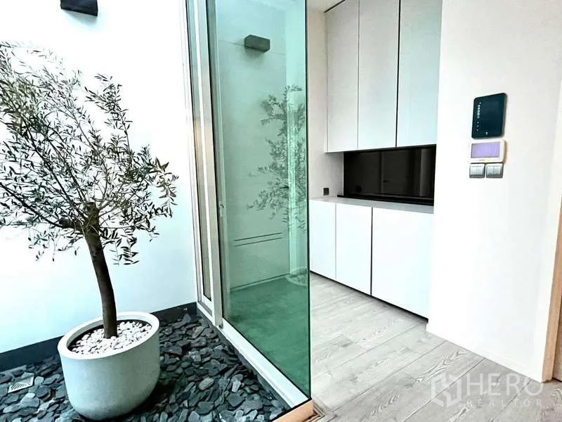 Detached House for rent or sale in Bang Phli, Samut Prakan - Small indoor atrium with a potted tree, pebbled floor and sliding glass partition.