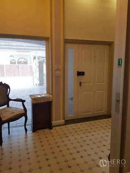 Townhouse for sale in Yan Nawa, Bangkok - Entry foyer with patterned tiles, front door and a private home lift beside an accent chair.