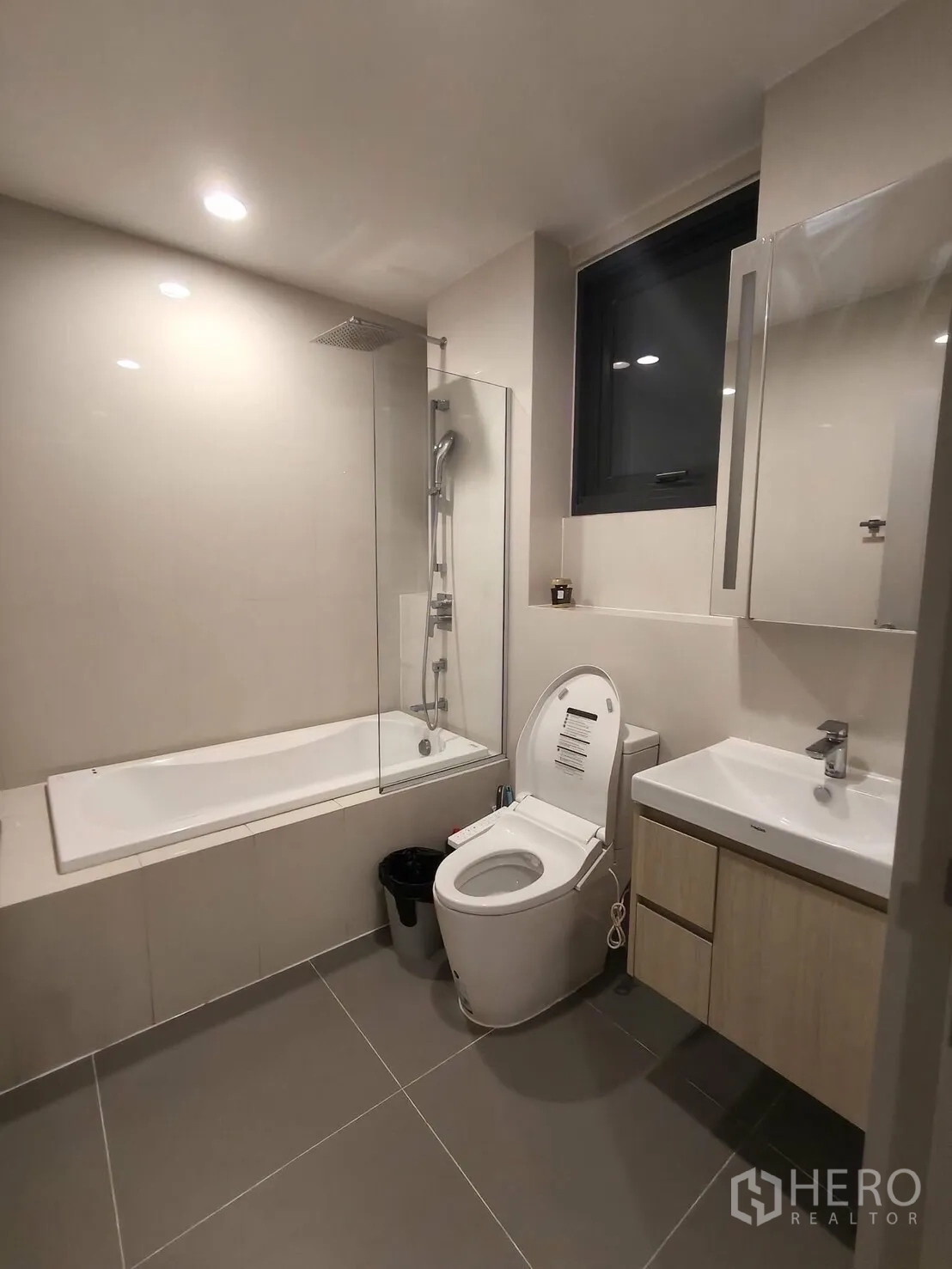 Condominium for rent in Khlong Toei, Bangkok - Spacious bathroom with a bathtub and shower, toilet with bidet seat, vanity, and a window.
