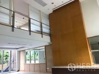 Townhouse for rent or sale in Yan Nawa, Bangkok - Double-height living room with mezzanine railing and tall feature wall.