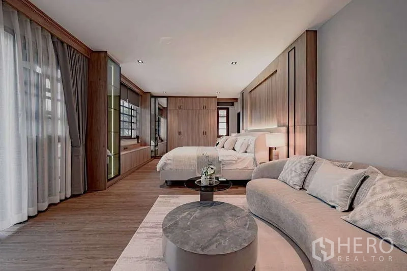Detached House for rent or sale in Phra Khanong, Bangkok - Master suite with curved sofa, twin coffee tables, and fitted wardrobes.