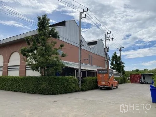 Warehouse for rent in Samut Sakhon - Corner view of the warehouse building with hedge and service area.
