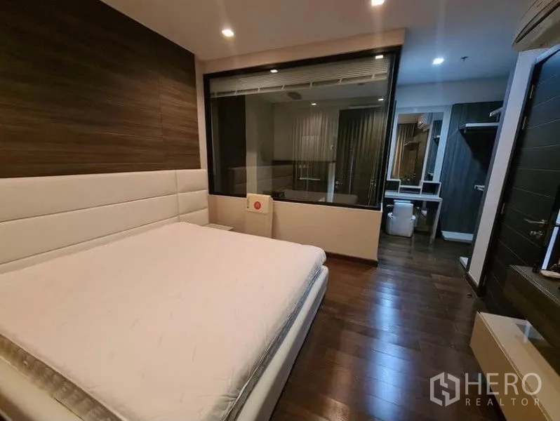 公寓 出租或出售在Huai Khwang, Bangkok - 主卧套间配玻璃隔断卫浴与温润木地板。