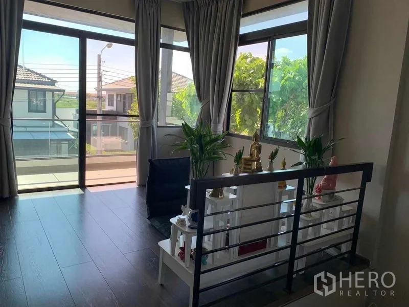 Detached House for rent or sale in Bang Phli, Samut Prakan - Upstairs landing with altar shelves, metal railing, sliding door to balcony and wraparound windows.