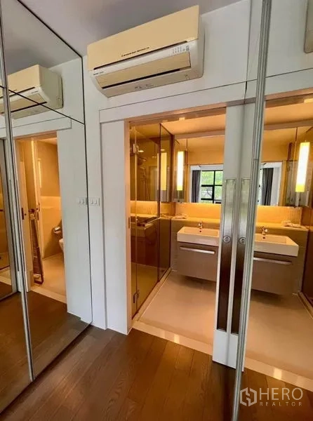 Condominium for rent in Watthana, Bangkok - Walk-through dressing area with mirrored wardrobes leading to a double-vanity bathroom.