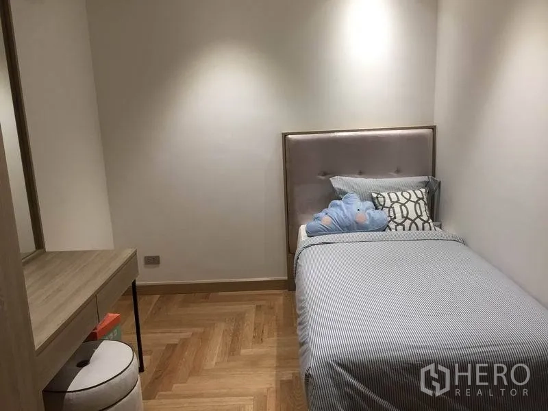 公寓 出售在Watthana, Bangkok - 温馨单人卧室，软包床头、梳妆台与人字形木地板。