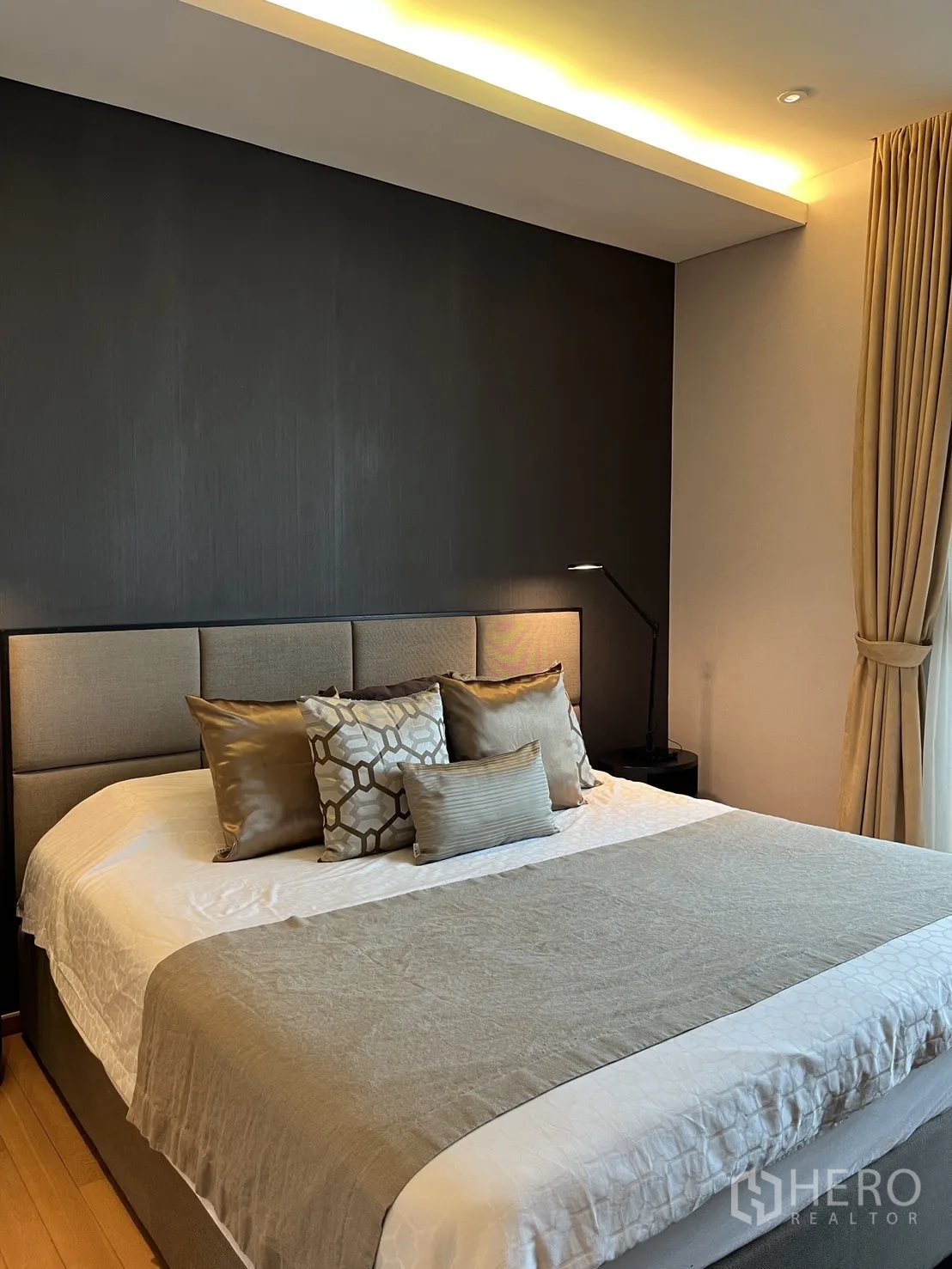 Condominium for rent in Watthana, Bangkok - Bedroom with feature wall, king bed, and warm ceiling lights.