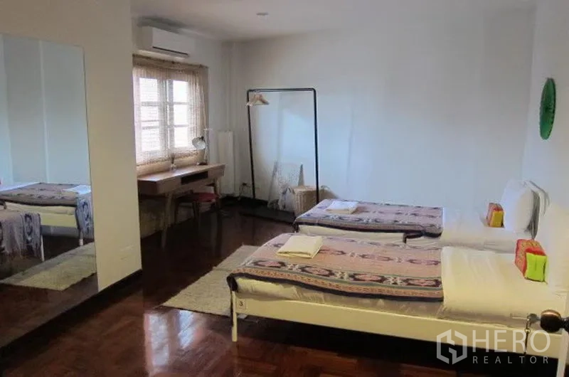 联排别墅 出租在Khlong Toei, Bangkok - 宽敞双床卧室，写字桌、大镜子与木地板。