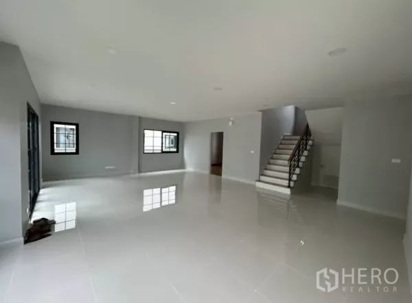 Detached House for rent in Bang Phli, Samut Prakan - Wide living area view showing stairs, multiple windows and neutral gray walls.