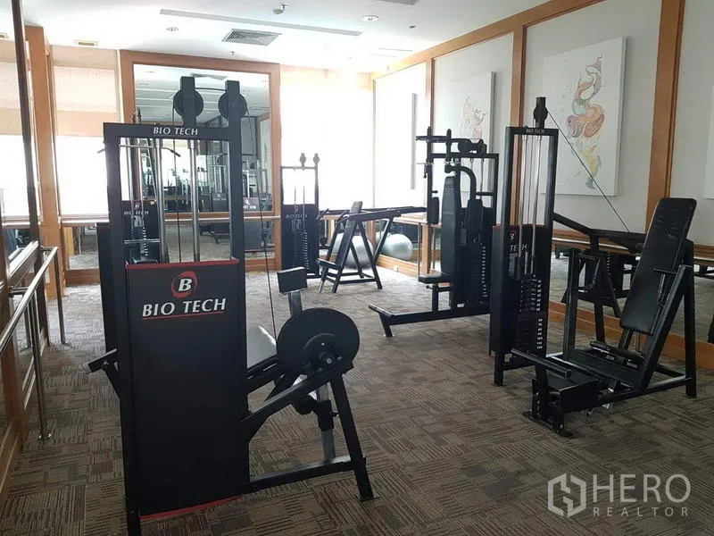 Condominium for rent in Pathum Wan, Bangkok - Fitness room equipped with weight machines and mirrors.