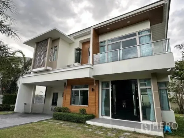 Detached House for rent in Lat Krabang, Bangkok - Modern two-storey detached house with balcony, large windows and double-door entry set behind a trimmed lawn in Bang Phli.