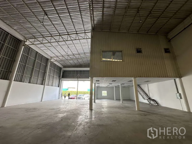 Factory for rent in Khlong Luang, Pathum Thani - Loading area looking to the main entrance with a large shutter and parking outside.