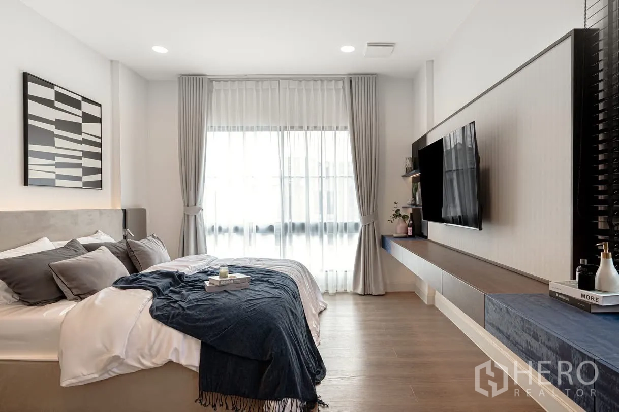 Detached House for rent in Saphan Sung, Bangkok - Bright bedroom with king bed, sheer drapes, and wall-mounted TV on a floating console.
