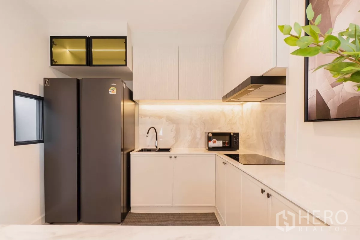 Detached House for rent or sale in Prawet, Bangkok - Bright kitchen corner with induction hob, sink and under-cabinet lighting