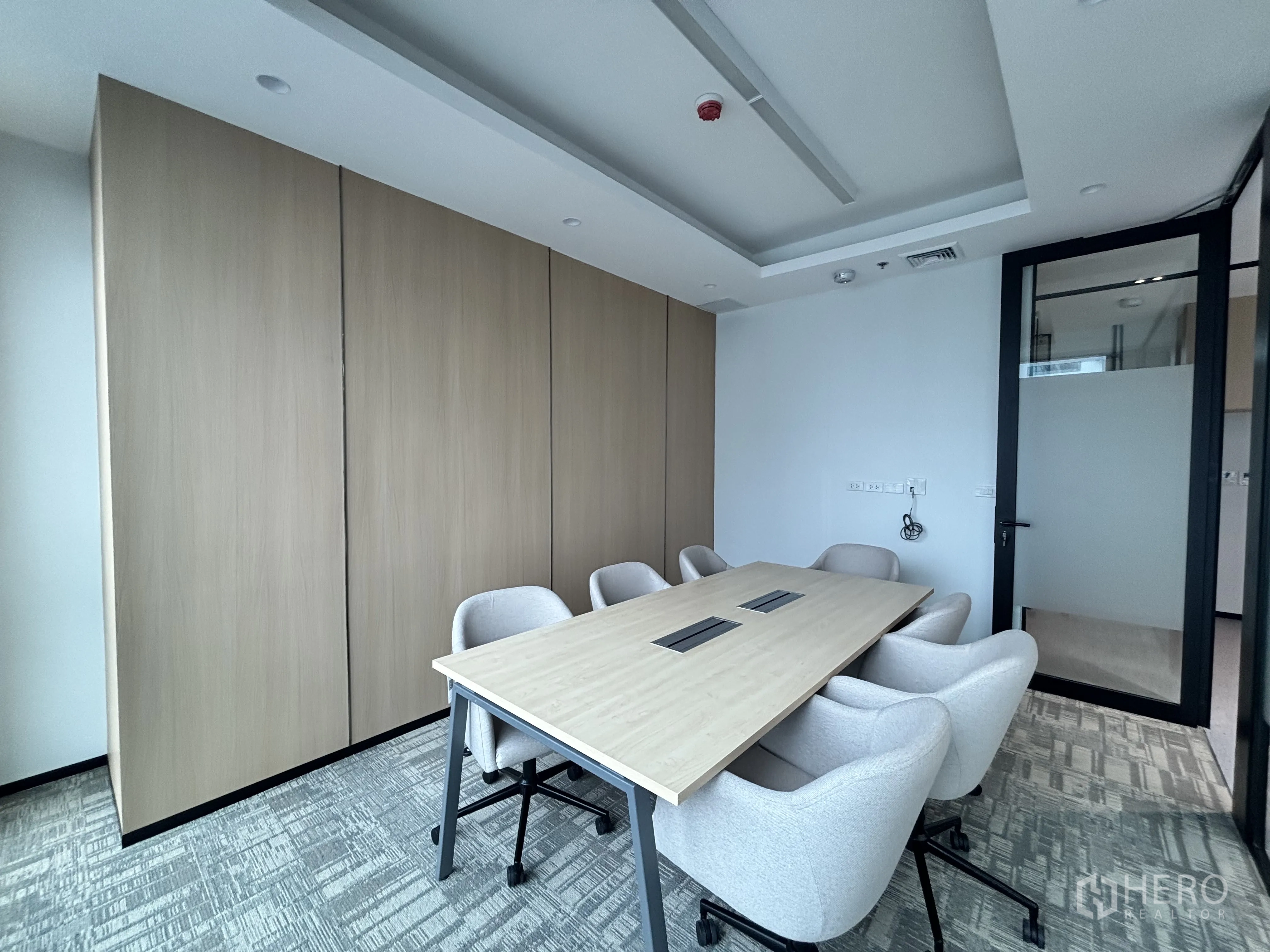 Office Space for rent in Huai Khwang, Bangkok - Private boardroom featuring wood-paneled wall, frosted glass door and recessed ceiling lighting.